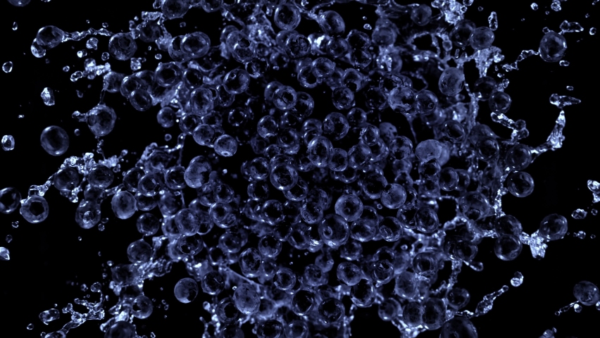 Super slow motion shot of rotating exploded blueberries with splashing water on black at 1000fps.