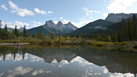 Scenery of Three Sisters mountain with autumn forest reflection on pond in Canmore at Banff national park, Canada