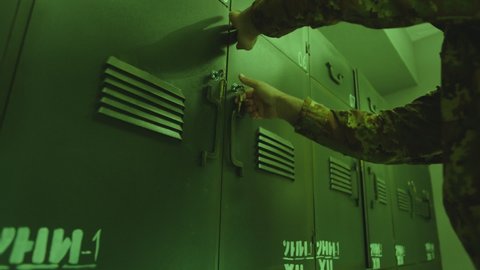 Close up view of green colored metallic military Locker Room . Soldiers putting bag inside safe and locking door . Military dressing room , storage . Swat or elite unit training concept . 