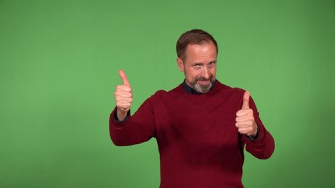 A middle-aged handsome Caucasian man shows a double thumb up to the camera with a smile - green screen background
