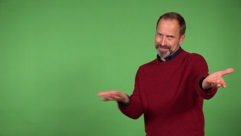 A middle-aged handsome Caucasian man motions to the camera in a gesture of invitation with a smile - green screen background