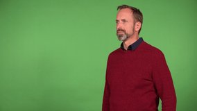 A middle-aged handsome Caucasian man eats a chocolate bar - green screen background