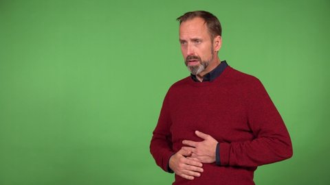 A middle-aged handsome Caucasian man has stomachache - green screen background