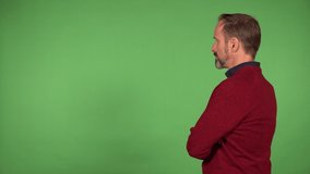 A middle-aged handsome Caucasian man looks at the green screen background