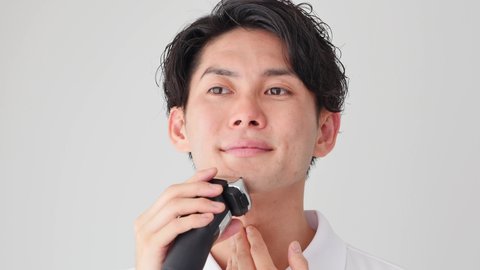 Asian man shaving with electric shaver