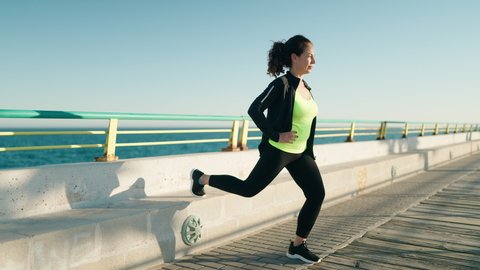 Middle age woman wearing sportswear training legs exercise at seaside