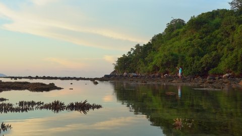 
a man take a photo on the rock.
Many staghorn corals emerge above the water during low tide.
The reflection from the sky in the sunrise is reflected in the sea of staghorn corals.
