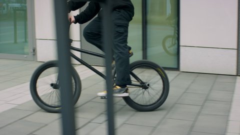 TRACKING Caucasian teenager kid riding his BMX bicycle through the city. Shot with 2x anamorphic lens
