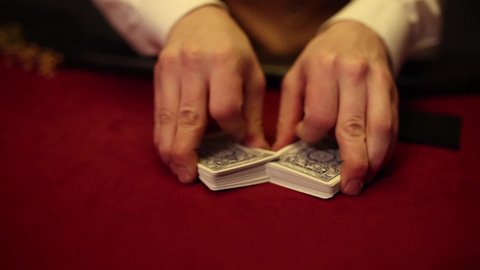 dealer at the poker table shuffling a deck of cards	