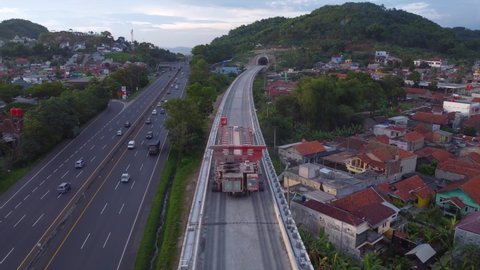 Bandung, March  2, 2022: Established Aerial View of Empty Box Girder Transporter Vehicles Crossing Elevated High Speed Rails On Padaleunyi Toll Roadside