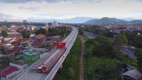 Bandung, March  2, 2022: Established Aerial View of Empty Box Girder Transporter Vehicles Crossing Elevated High Speed Rails On Padaleunyi Toll Roadside