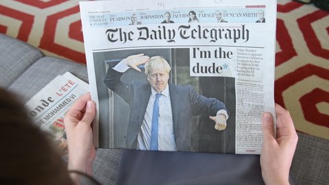 Paris, France - Jul 24, 2019: POV woman hand reading newspaper in living room with Boris Johnson appears on cover of Daily Telegraph as he becomes UK United Kingdom Prime Minister - i'm the dude title