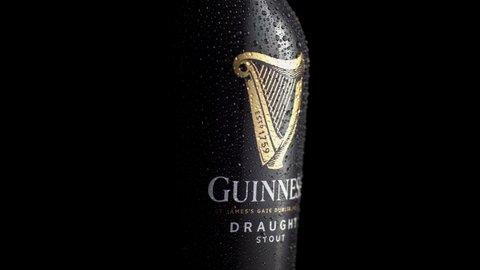 Dublin, Ireland - March 15, 2022: Irish Guinness dark beer label logo on a bottle close up rotating on a black background and isolated.
