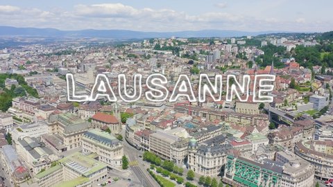 Inscription on video. Lausanne, Switzerland. Flight over the central part of the city. La Cite is a district historical centre. Neon white effect text, Aerial View, Departure of the camera