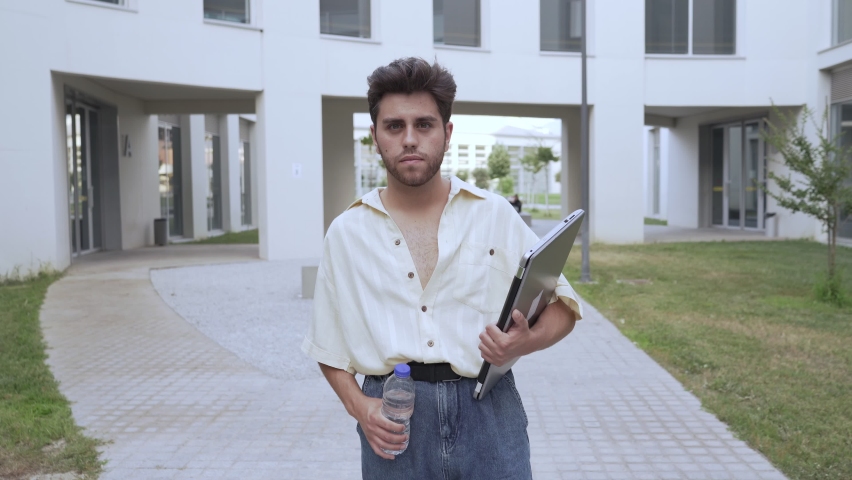 man walking in university with laptop and bottle of water. 4k