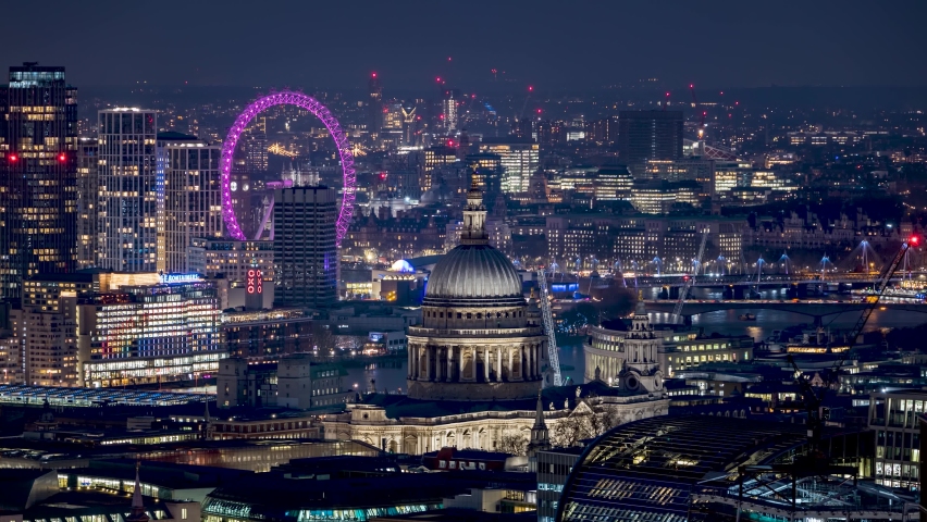 London, UK - March 10th 2022: evening time lapse of the skyline of London with St. Pauls Cathedral, river Thames and Big Ben tower right behind the London Eye