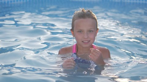 smiling girl in swimming pool, child is playing. Summer vacation or classes. Summertime and swimming activities for happy children on the pool.