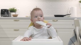 Baby boy sitting on high chair for babies playing with smartphone, cute toddler holding mobile phone, child and modern technology concept. High quality 4k footage