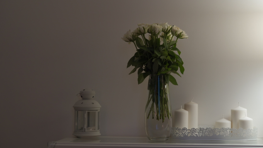 Console table with bouquet of flowers lit by a table lamp in the living room, apartment decoration background. High quality 4k footage