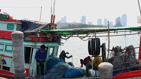 Pattaya , Chonburi , Thailand - 12 03 2021: Four people fixing nets and then one goes inside the cabin, Pattaya Fishing Dock, Chonburi, Thailand.