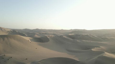 Aerial: Tourist dune buggies explore tractless desert sand in Peru