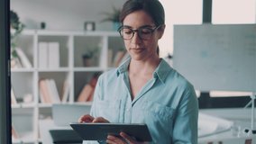 Video of businesswoman working with digital tablet while standing at the office. - Powered by Shutterstock - Get 15% off with code: PIKWIZARD15