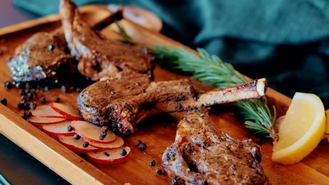 Grilled Lamb Chops with Rosemary and vegetables. Roasted Cutlets on Creative Restaurant Backdrop. Mutton Ribs with Spices and Sauce