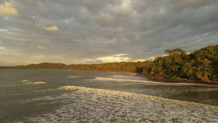 Aerial shot of a sunset in Costa Rica. Yellow sky with waves coming from pacific ocean. Pavones, surf area