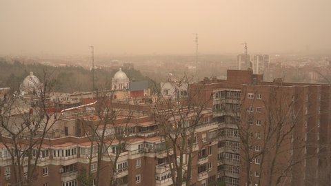 MADRID, SPAIN. March 15 2022. Wide pan shot of a panoramic view of Madrid with Royal Palace and Almudena Cathedral amid an orange sky due to a dust storm from the Sahara desert reducing visibility