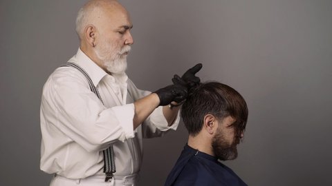 Hair coloring in gray color process. Hairdresser applying colorful tint on man models hair. Coloring man hair process. Dyed hair for a bearded hipster guy.