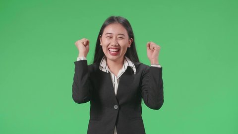 Happy Asian Business Woman Celebrating While Standing On Green Screen In The Studio

