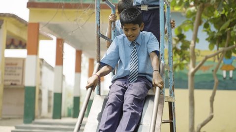 school kids in unifrom busy playing on slide while at school - concept of childhood growth ,leisure activities and having fun