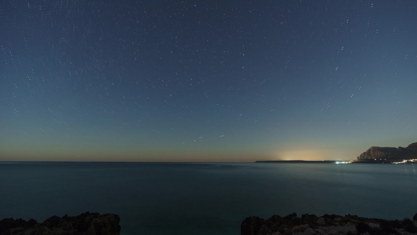 Startrails around polaris over rocky coastline of mediterranean sea with clear turquoise water at nature reserve of monte Cofano, Sicily