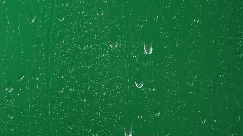 Water rainfall, rain drops falling on window glass over chroma key green screen