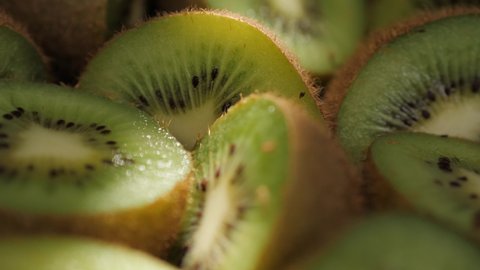 Kiwi fruit. Macro shot camera pans down and showing cutting kiwi fruits in shadow. Macro shot
