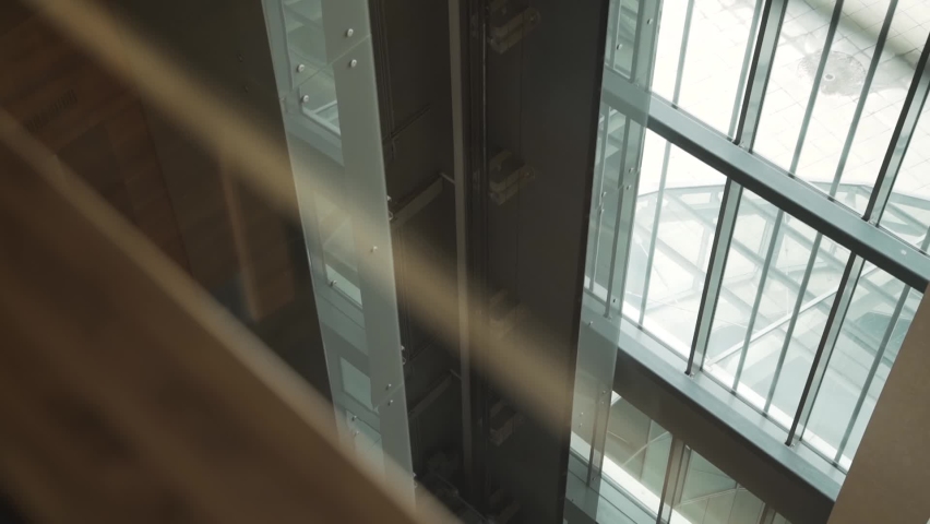 Empty open glass transparent elevator car rises up inside the building. Modern stylish elevator design indoors, reflection on glass. The work of the lifting mechanism. Royalty-Free Stock Footage #1088279109