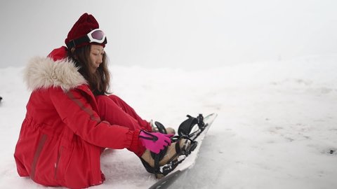 Young asian girl snowboarding on snow slope in winter ski resort. Ski elevator on snow mountain. Winter activity