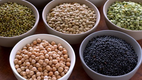 Legumes assortment. Variety of dry beans and lentils in bowls. Table spin.