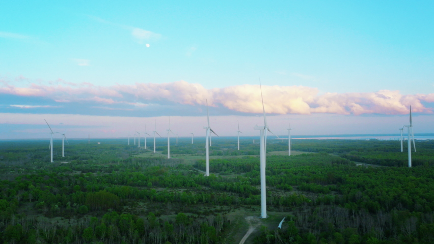 Scenic Aerial Drone Footage of Environmental Wind Turbines in a Forest Near the Sea. Green Renewable Energy Park with VFX Augmented Reality Holograms Shows Internet of Things Online Connectivity. Royalty-Free Stock Footage #1088284701