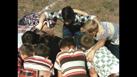 1940s: Field, boys huddle in circle, stand, run. Boy sits on folding chair, puts arm on pillow on rolling tray table.