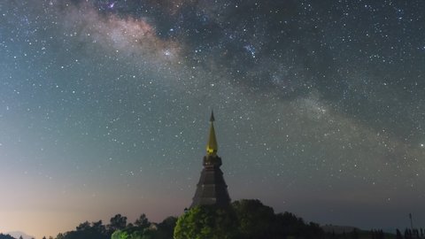 Time Lapse 4K of The Milky Way Galaxy moving over a sacred temple at Doi Inthanon National Park, Chiang Mai, Thailand. Night lapse from night to day. Starry night.