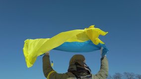 War in Ukraine, Young woman holding national flag of Ukraine over her head during russian occupation. Support, Save, Help, Pray for Ukraine.  - Powered by Shutterstock - Get 15% off with code: PIKWIZARD15