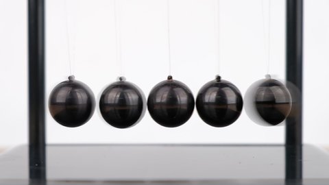 Slow motion, Macro shot, Newton's Cradle metal balls on wooden desk, swinging metal balls, Close up.