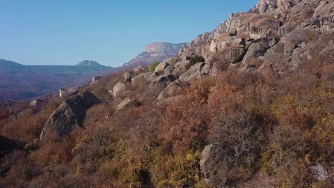 Fly over rocky outcrop in autumn mountains