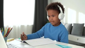 Cute african ethnicity school boy elearning with online tutor at home. Mixed race child wearing headphones using computer app video calling watching online class lesson. Online education. 4k footage