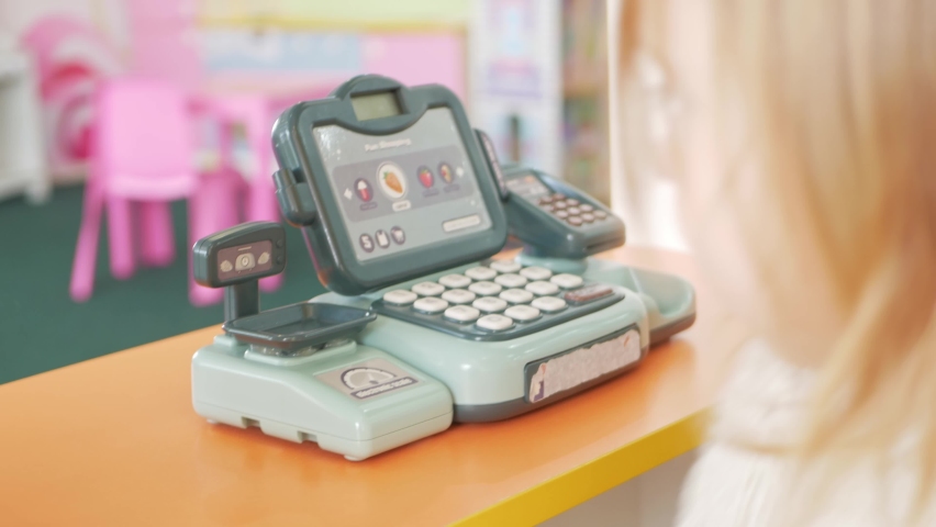 child plays with cash register, device for store, calculator, buttons and numbers. Play center, kindergarten. Clicks