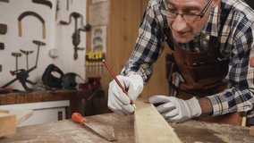 Working carpenter is drawing on a piece of wood. High quality 4k footage