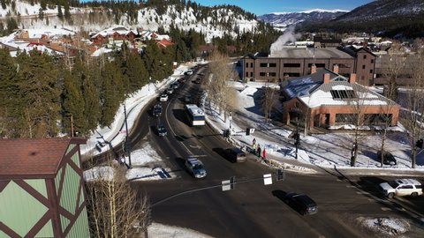 Aerial shot over a road in a town in Colorado, USA with snow covered mountains in the background with red bricked buildings in the foreground at daytime.