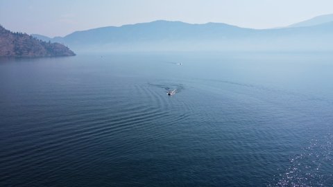 Two speed boats driving over deep, blue Okanagan Lake on a hot summer day in Canada. High aerial pedestal shot