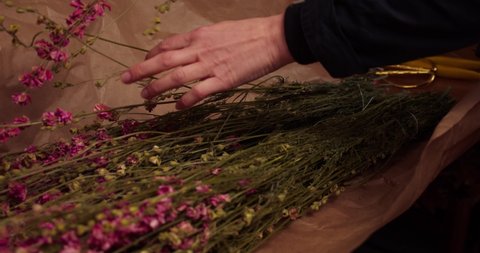 Florist unwrapping natural dried flowers and handling them. Gimbal, close up